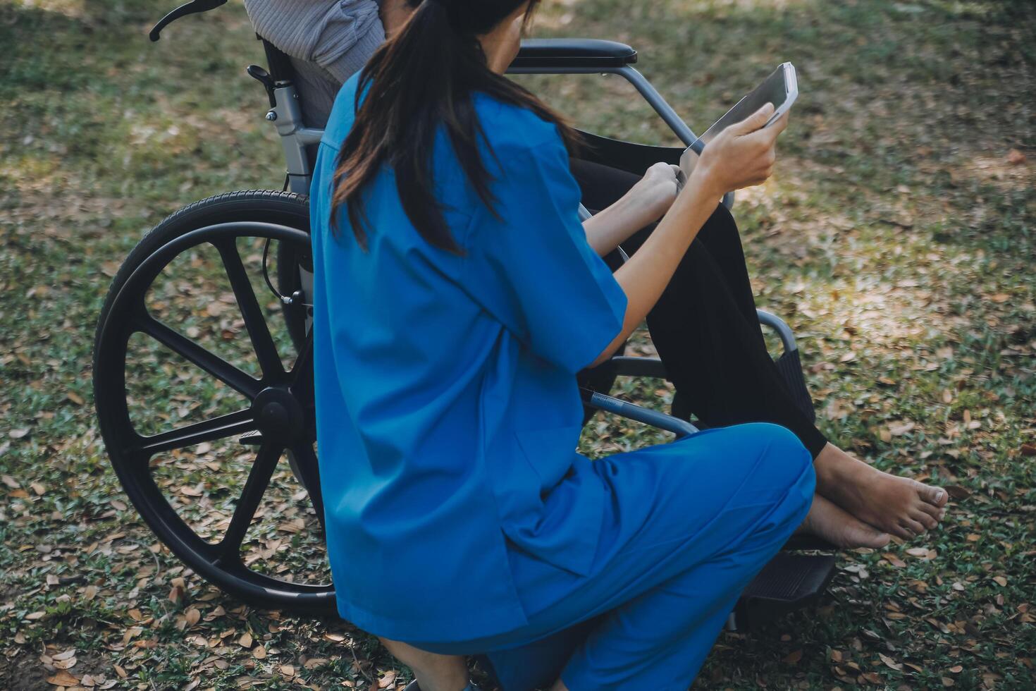 Elderly asian senior woman on wheelchair with Asian careful caregiver and encourage patient, walking in garden. with care from a caregiver and senior health insurance in sun light photo