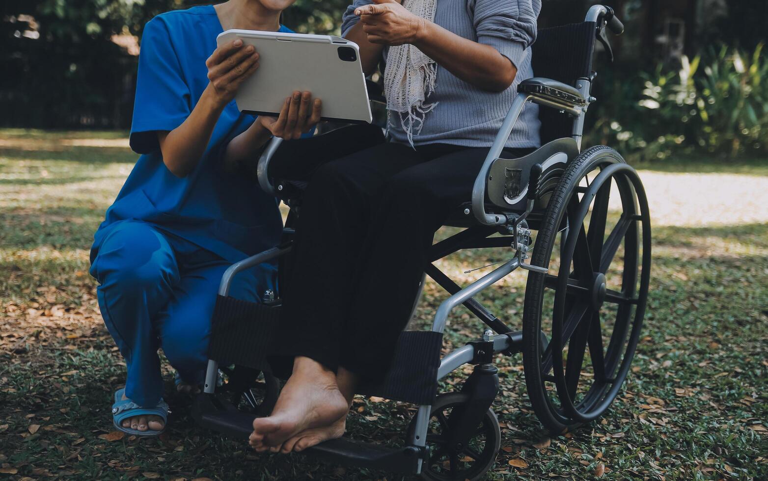 Elderly asian senior woman on wheelchair with Asian careful caregiver and encourage patient, walking in garden. with care from a caregiver and senior health insurance in sun light photo