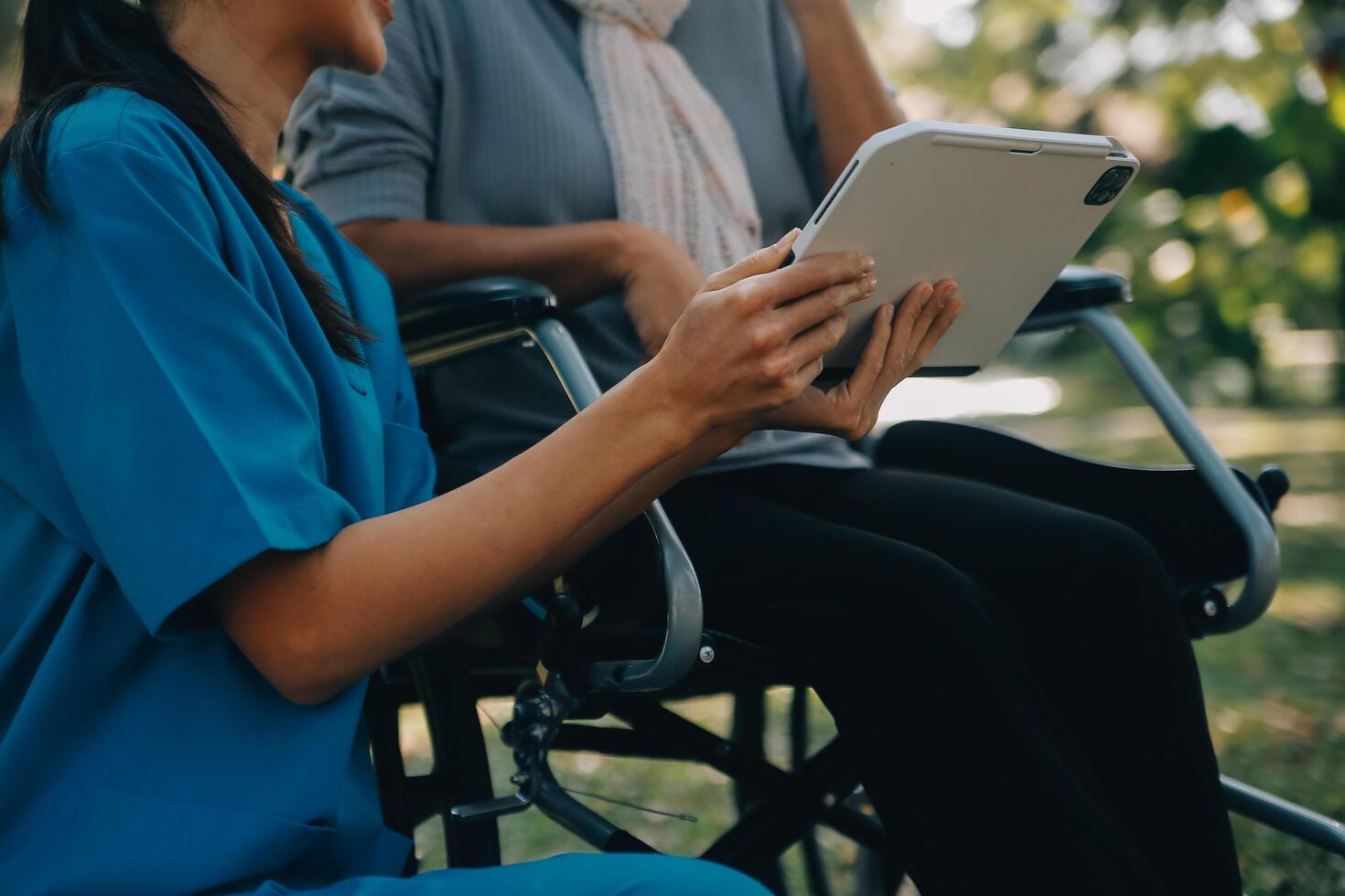 Elderly asian senior woman on wheelchair with Asian careful caregiver and encourage patient, walking in garden. with care from a caregiver and senior health insurance in sun light photo