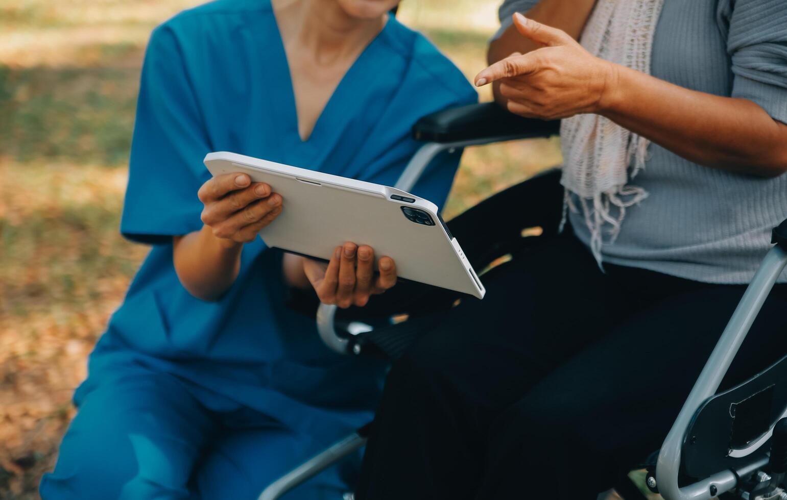 Elderly asian senior woman on wheelchair with Asian careful caregiver and encourage patient, walking in garden. with care from a caregiver and senior health insurance in sun light photo