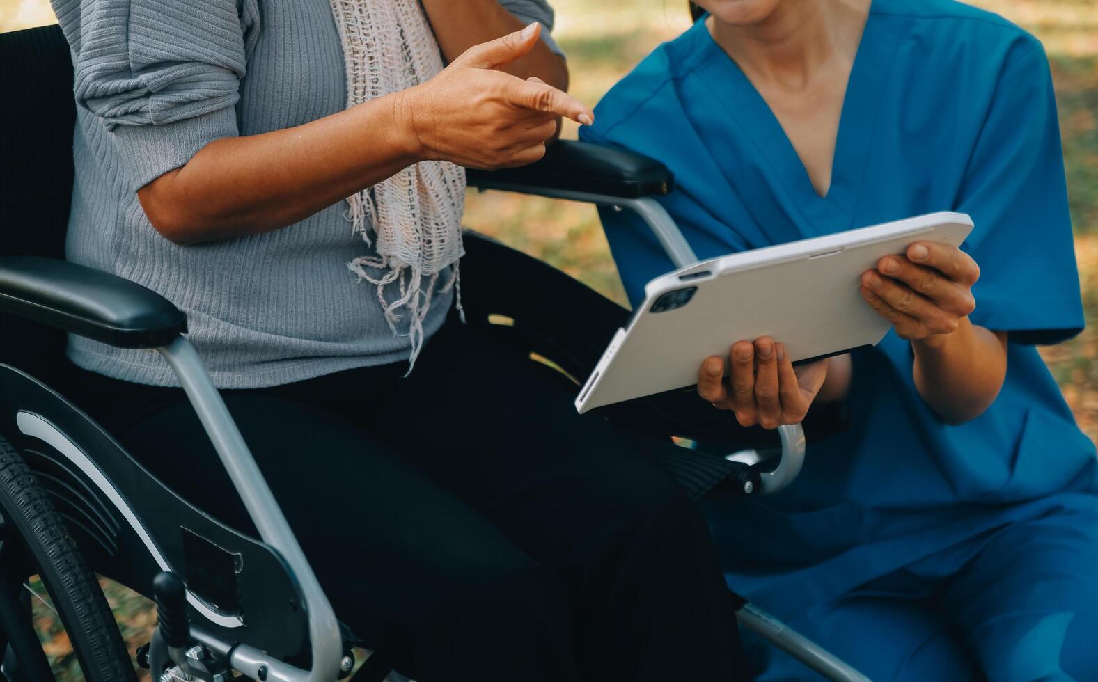 Elderly asian senior woman on wheelchair with Asian careful caregiver and encourage patient, walking in garden. with care from a caregiver and senior health insurance in sun light photo