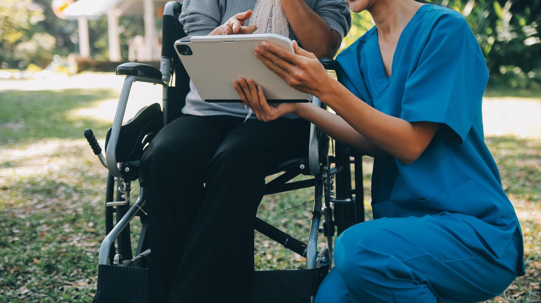 Elderly asian senior woman on wheelchair with Asian careful caregiver and encourage patient, walking in garden. with care from a caregiver and senior health insurance in sun light photo