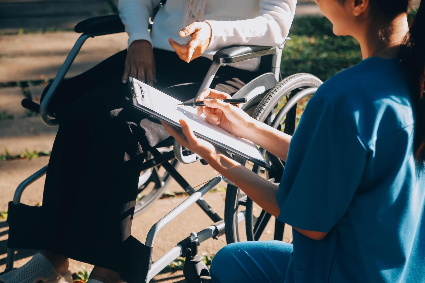 Nursing staff talking to an elderly person sitting in a wheelchair. photo