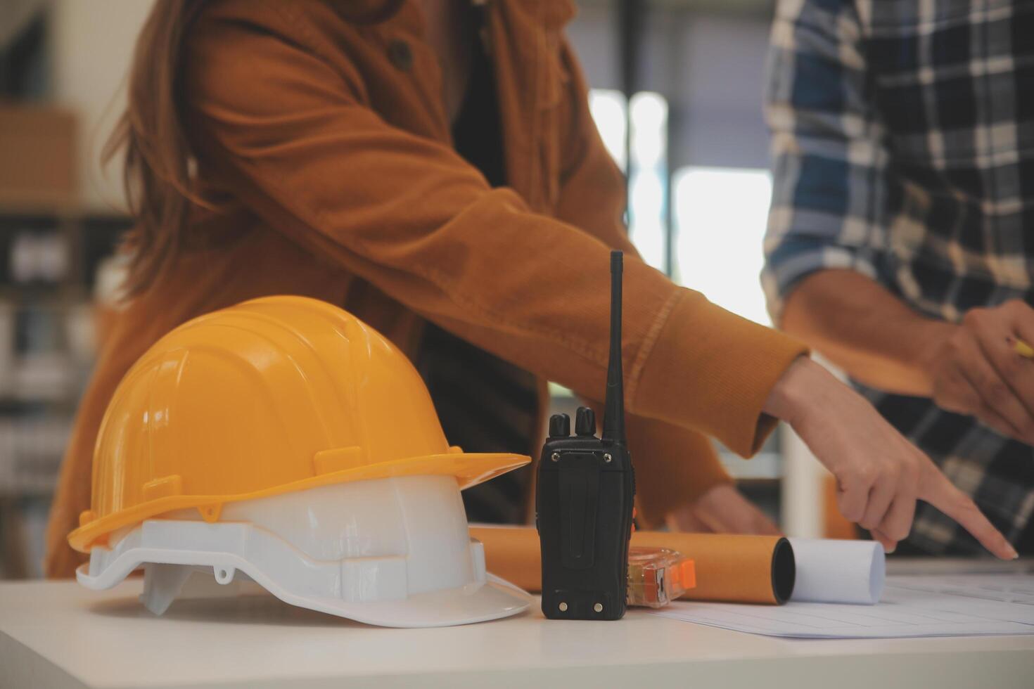 Male and Female Industrial Engineers in Hard Hats Discuss New Project while Using Laptop. They Make Showing Gestures.They Work in a Heavy Industry Manufacturing Factory. photo