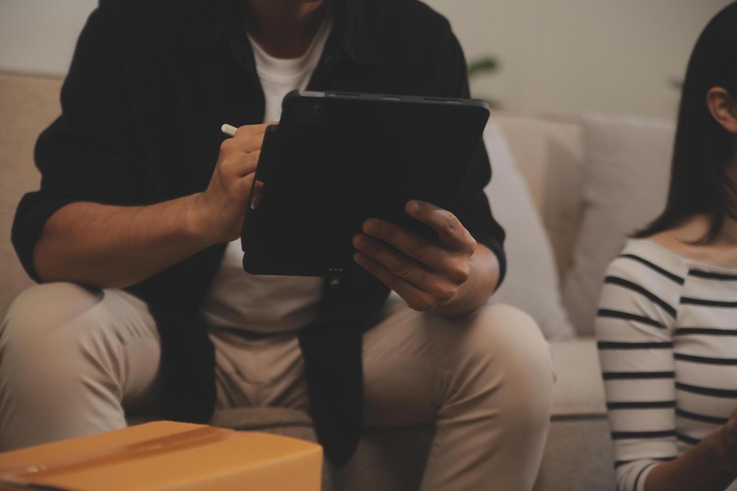 Two Asian blogger showing clothes in front of the camera to recording vlog video live streaming at her shop. Online Shopping Cart notion. on sofa at home photo