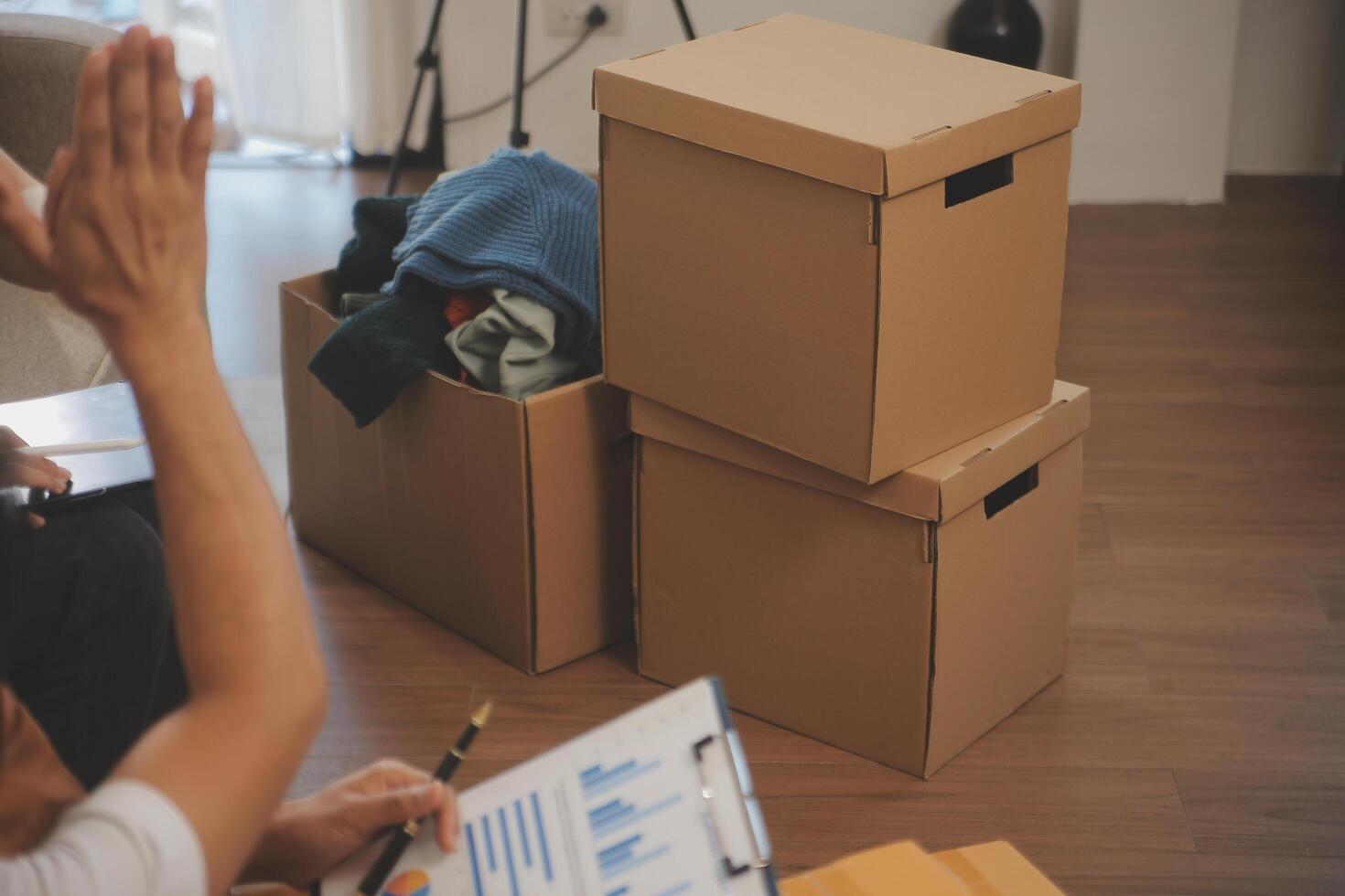 Two Asian blogger showing clothes in front of the camera to recording vlog video live streaming at her shop. Online Shopping Cart notion. on sofa at home photo