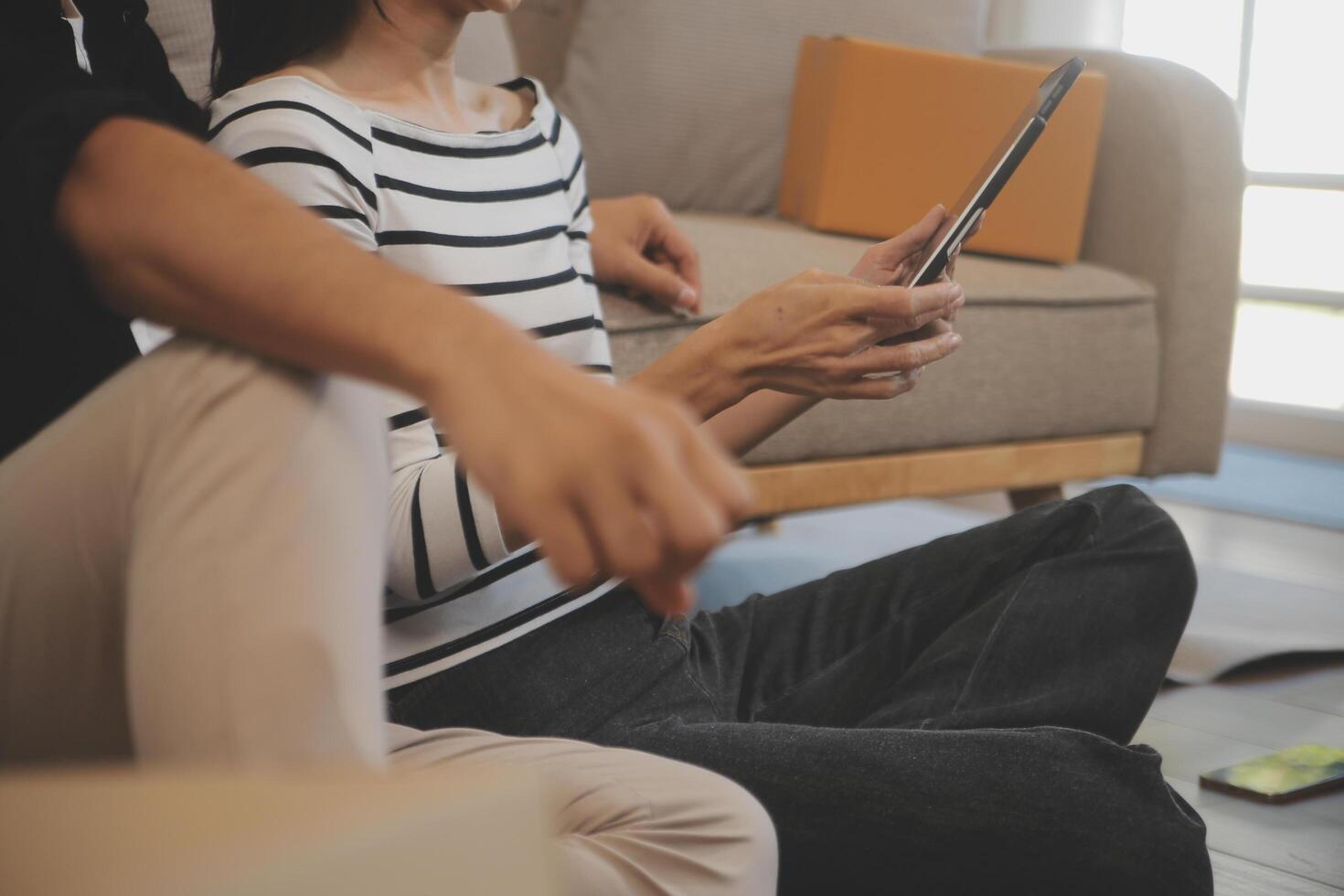 Two Asian blogger showing clothes in front of the camera to recording vlog video live streaming at her shop. Online Shopping Cart notion. on sofa at home photo