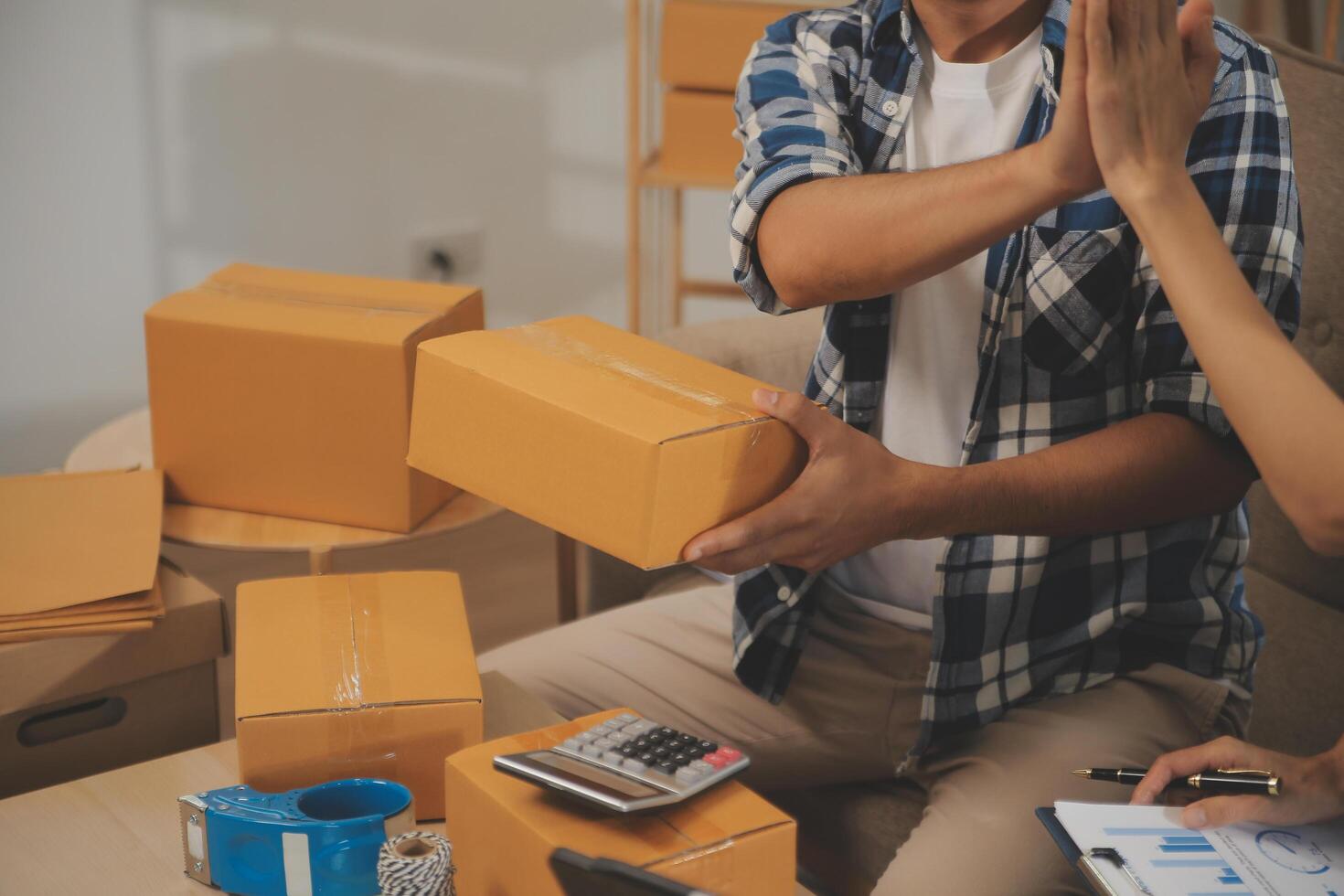 Two Asian blogger showing clothes in front of the camera to recording vlog video live streaming at her shop. Online Shopping Cart notion. on sofa at home photo
