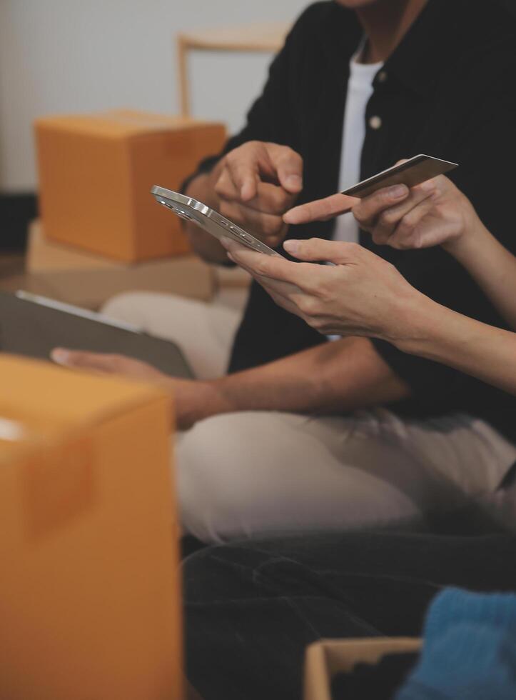 Two Asian blogger showing clothes in front of the camera to recording vlog video live streaming at her shop. Online Shopping Cart notion. on sofa at home photo