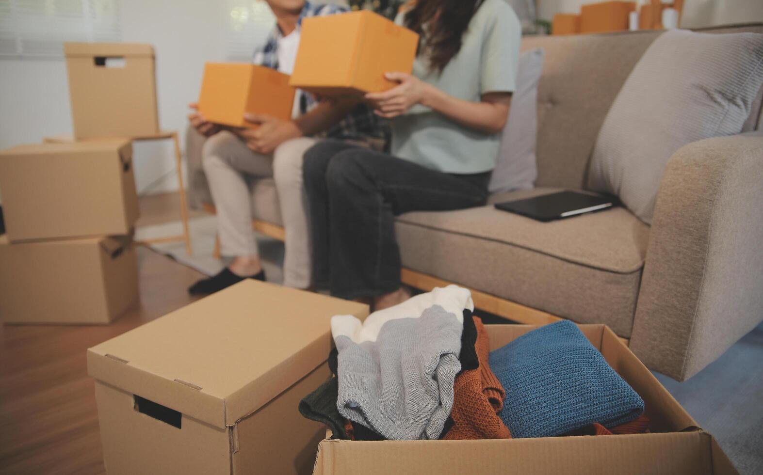 Two Asian blogger showing clothes in front of the camera to recording vlog video live streaming at her shop. Online Shopping Cart notion. on sofa at home photo