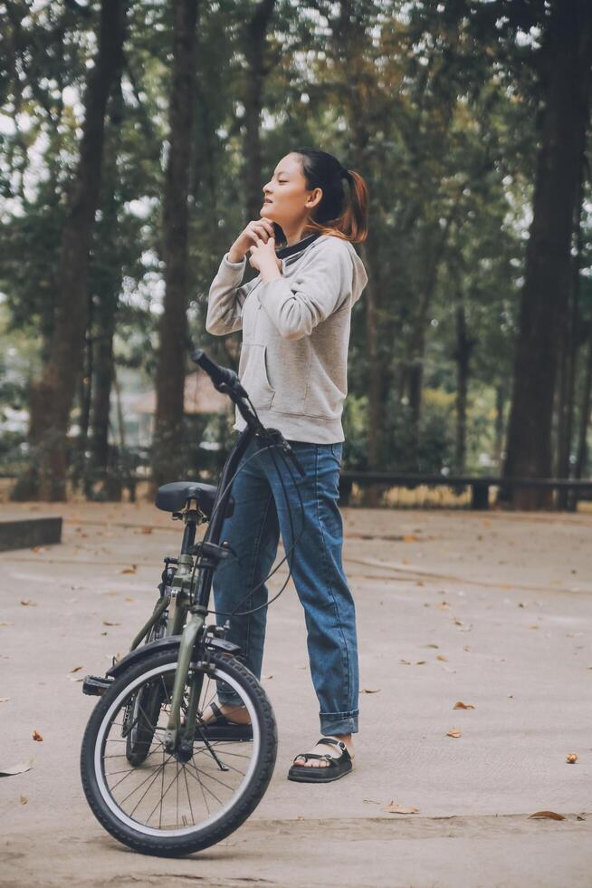 Happy Asian young woman walk and ride bicycle in park, street city her smiling using bike of transportation, ECO friendly, People lifestyle concept. photo