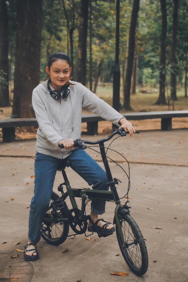 Happy Asian young woman walk and ride bicycle in park, street city her smiling using bike of transportation, ECO friendly, People lifestyle concept. photo