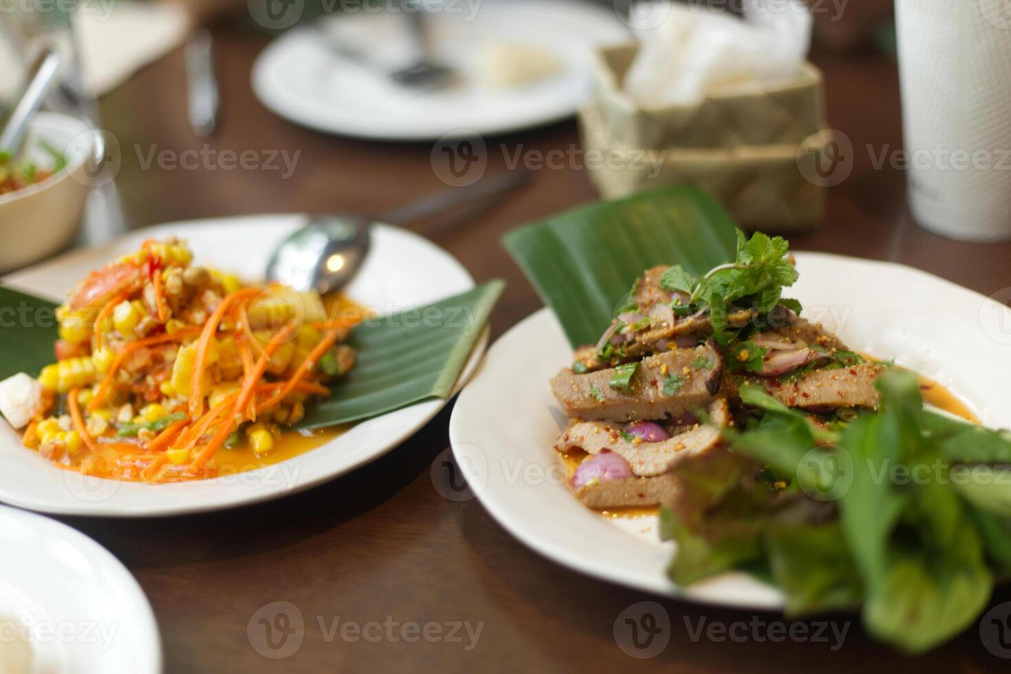 Thai Papaya Salad with Corn serve on banana leaf decoration on plate  and Spicy Grilled Pork Neck on wooden table photo