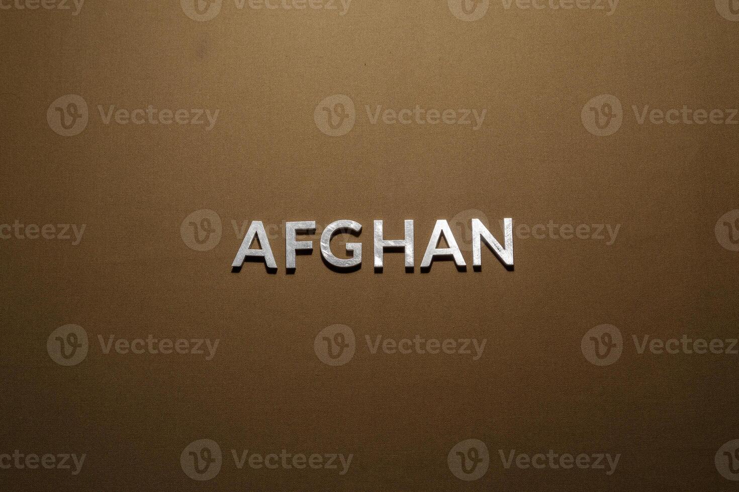 the word afghan laid with silver metal letters on rough tan khaki canvas fabric photo