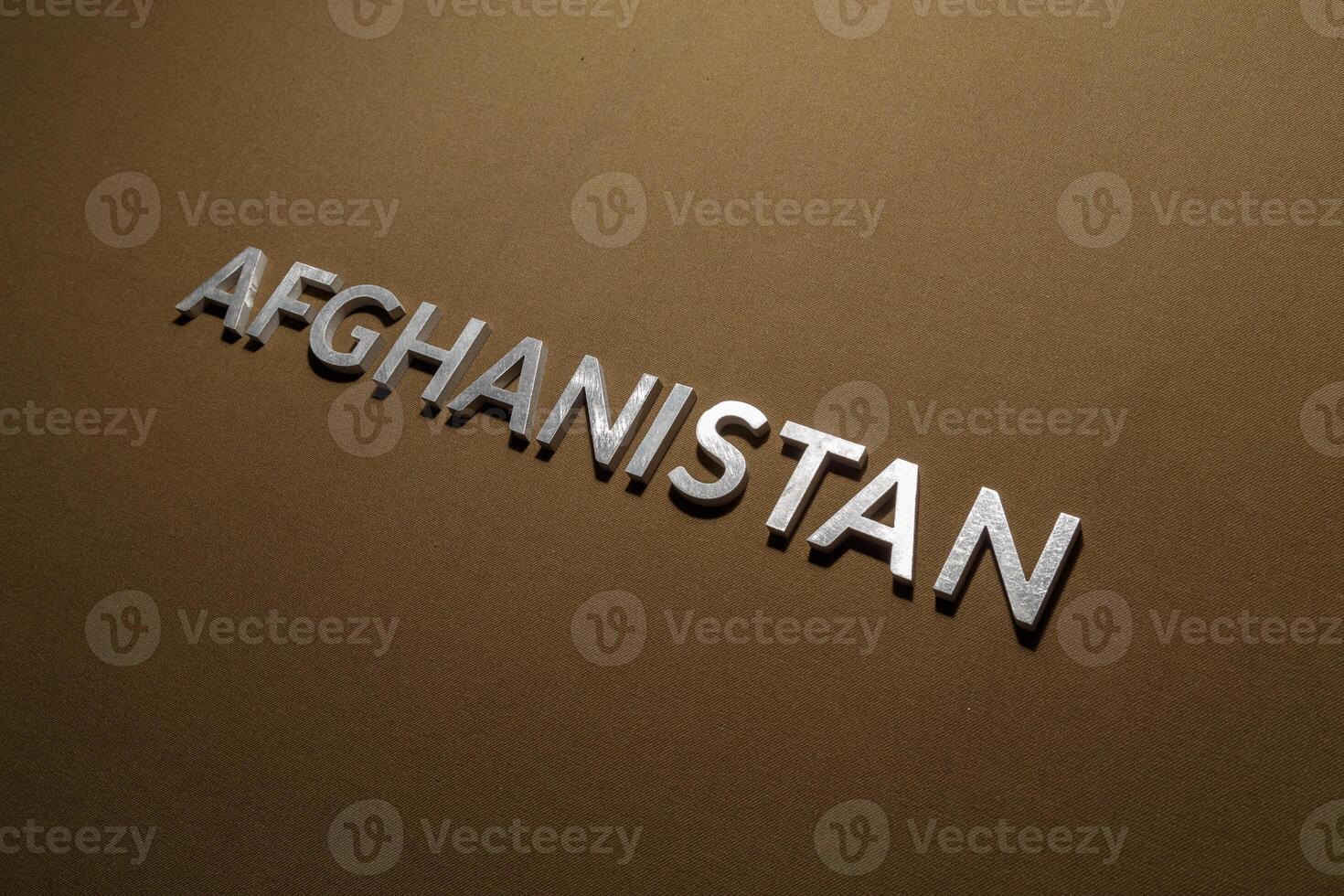 the word afghanistan laid with silver metal letters on rough tan khaki canvas fabric photo