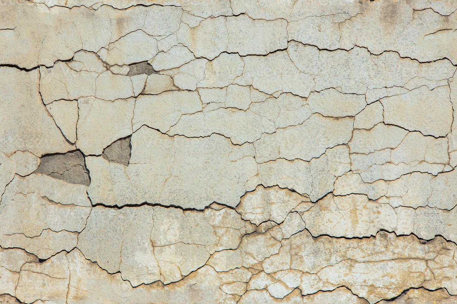 cracked white concrete wall under direct sun light full frame background and seamless texture photo