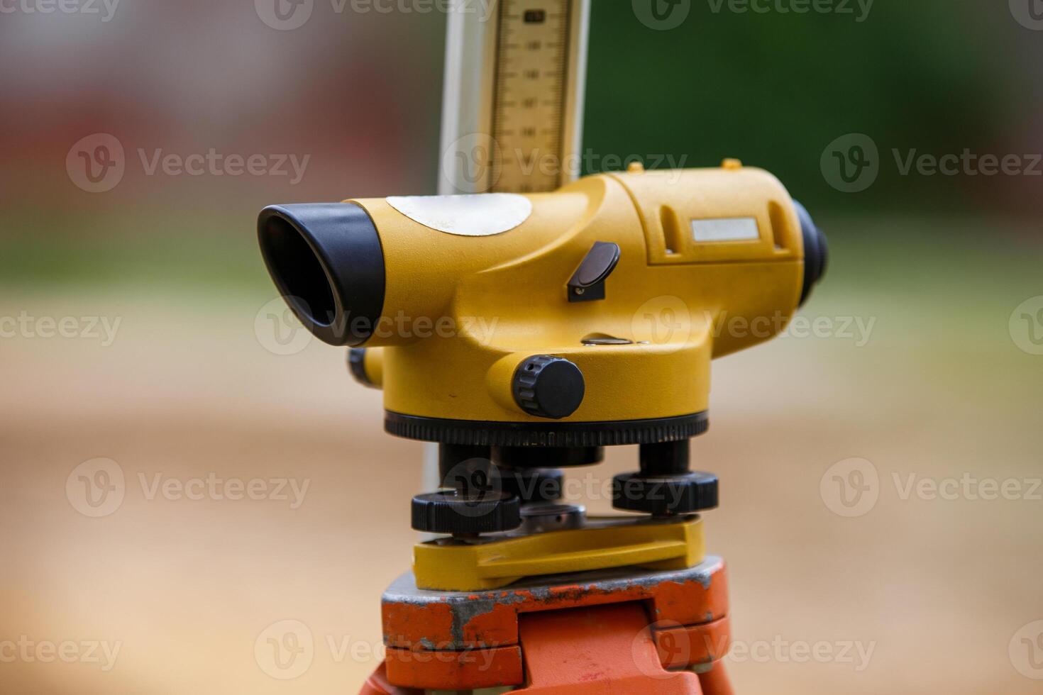 Yellow theodolite on a tripod and a ruler with a blurred background. Geodetic measurements. photo