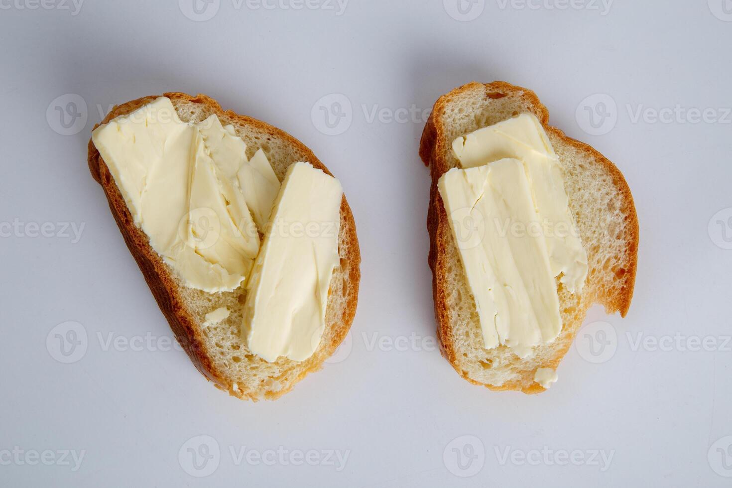 two pieces of white bread with butter on white background photo