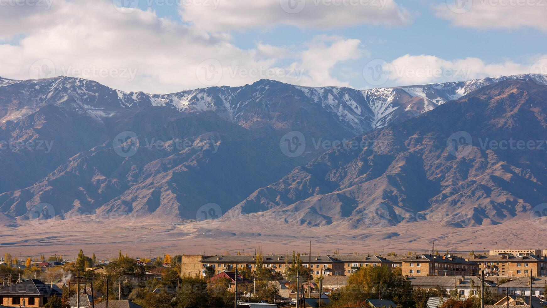 pequeño kirguís pueblo balykchi paisaje urbano en frente de masivo montaña cresta foto