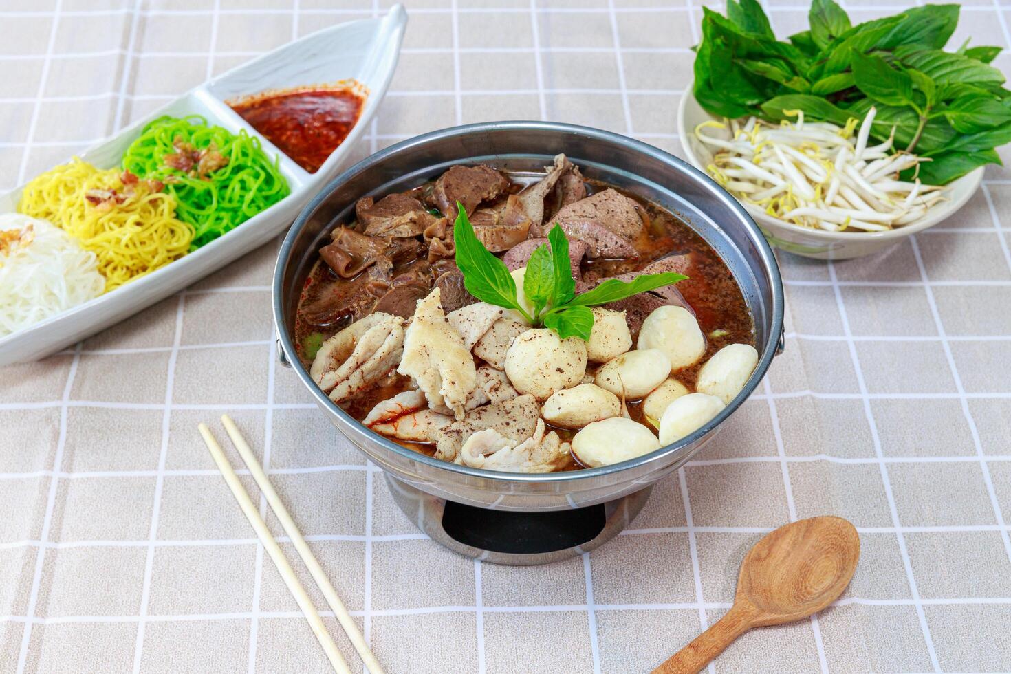 Braised Beef Soup in Hot Pot. One type of noodle dish that is popular in Thailand is called Boat Noodle Hot Pot. Served with different kinds of noodles such as rice vermicelli, thin noodles photo