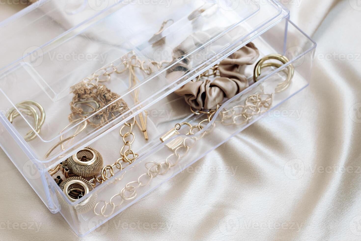 Gold jewelry earrings bracelets in a transparent organizer photo