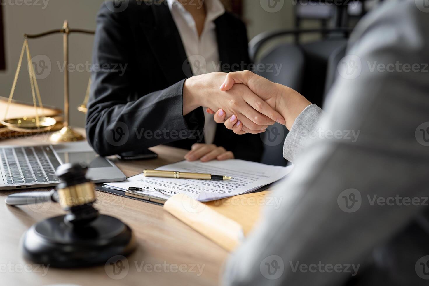 Gavel Justice hammer on wooden table with judge and client shaking hands after adviced in background at courtroom, lawyer service concept. photo