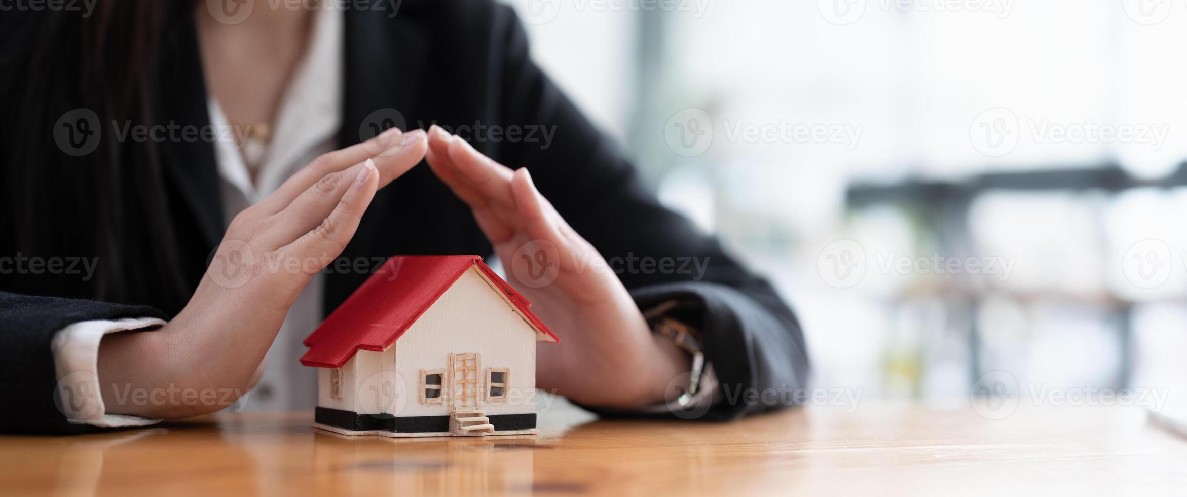 Wooden toy house protected by hands with copy space. Home insurance concept. banner ratio photo