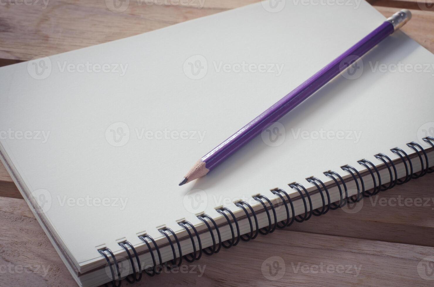 blank notebook with pencil on wooden table - still life photo