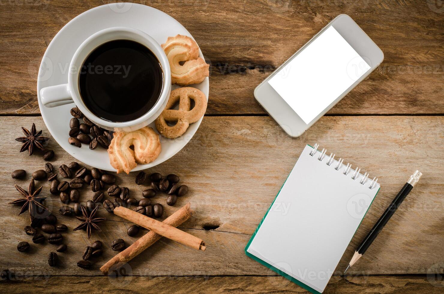 café galletas y teléfono inteligente cuaderno en un de madera mesa en el Mañana. foto