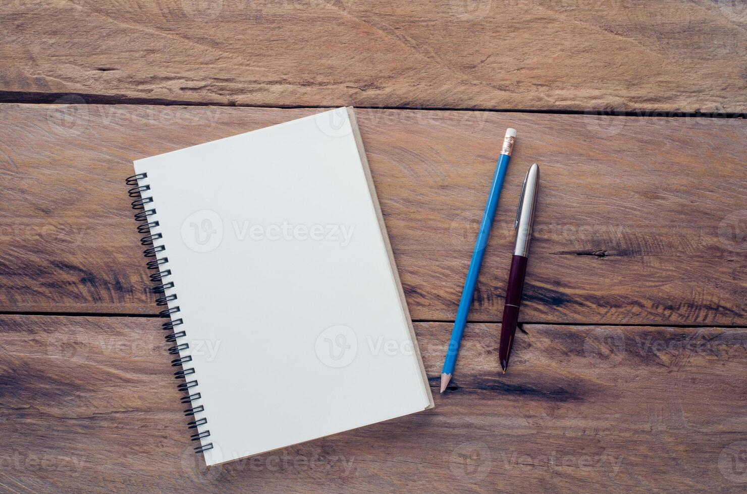 blanco cuaderno con lápiz y bolígrafo en de madera mesa - todavía vida foto