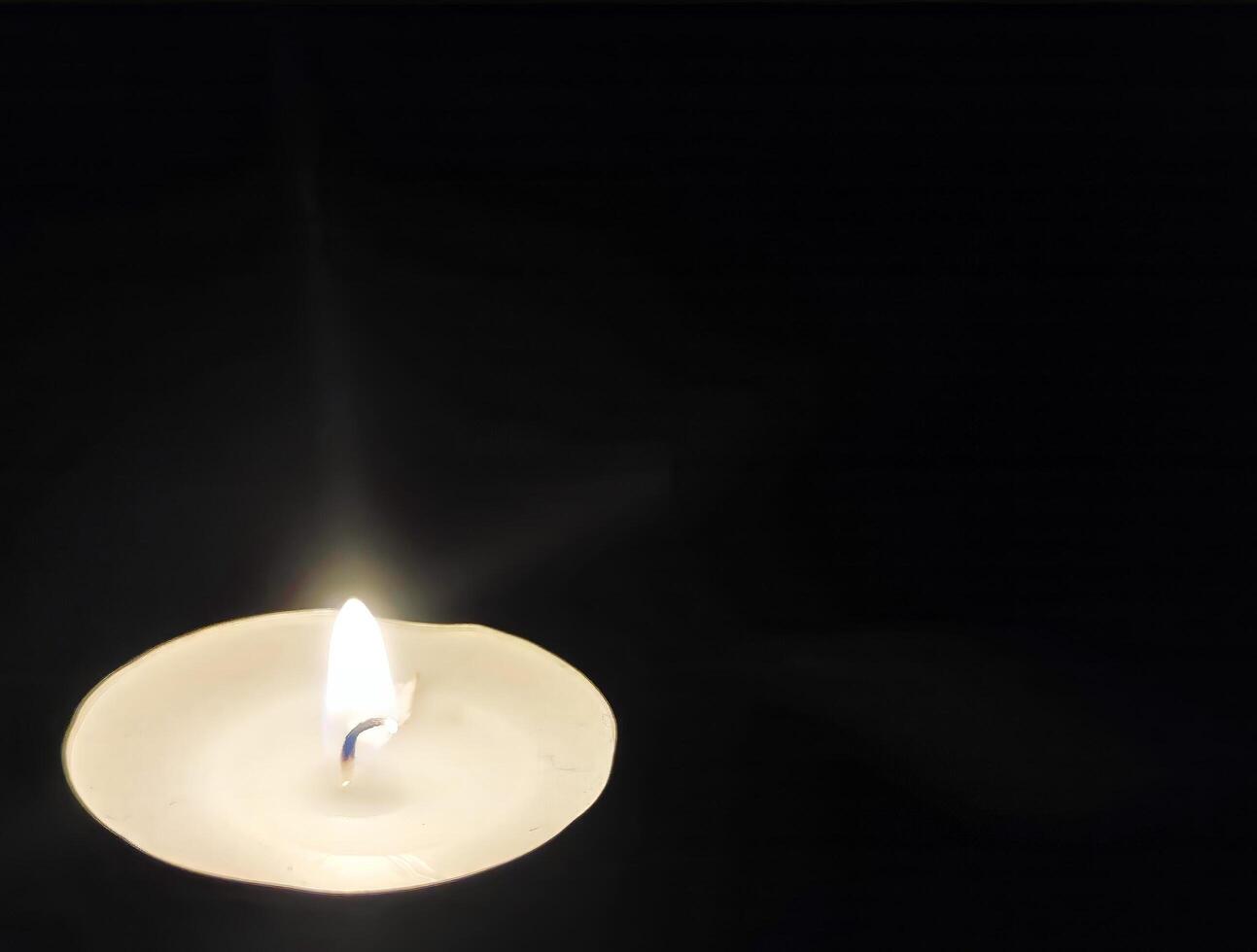 Single candle isolated over black background, symbolic photo concept