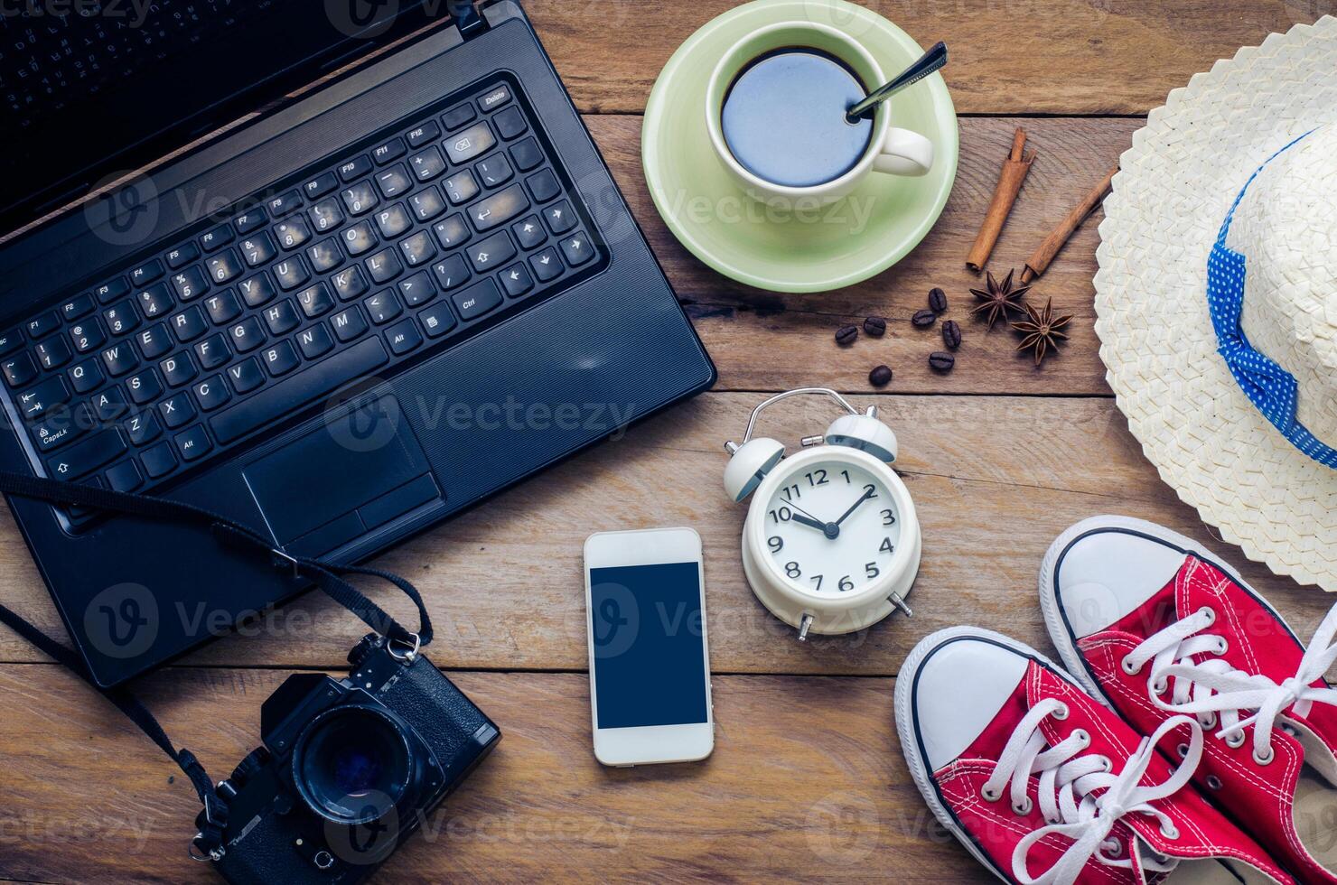 Coffee cup, notebook, alarm clock headphone smart phone and costume on the wooden floor in the morning. photo