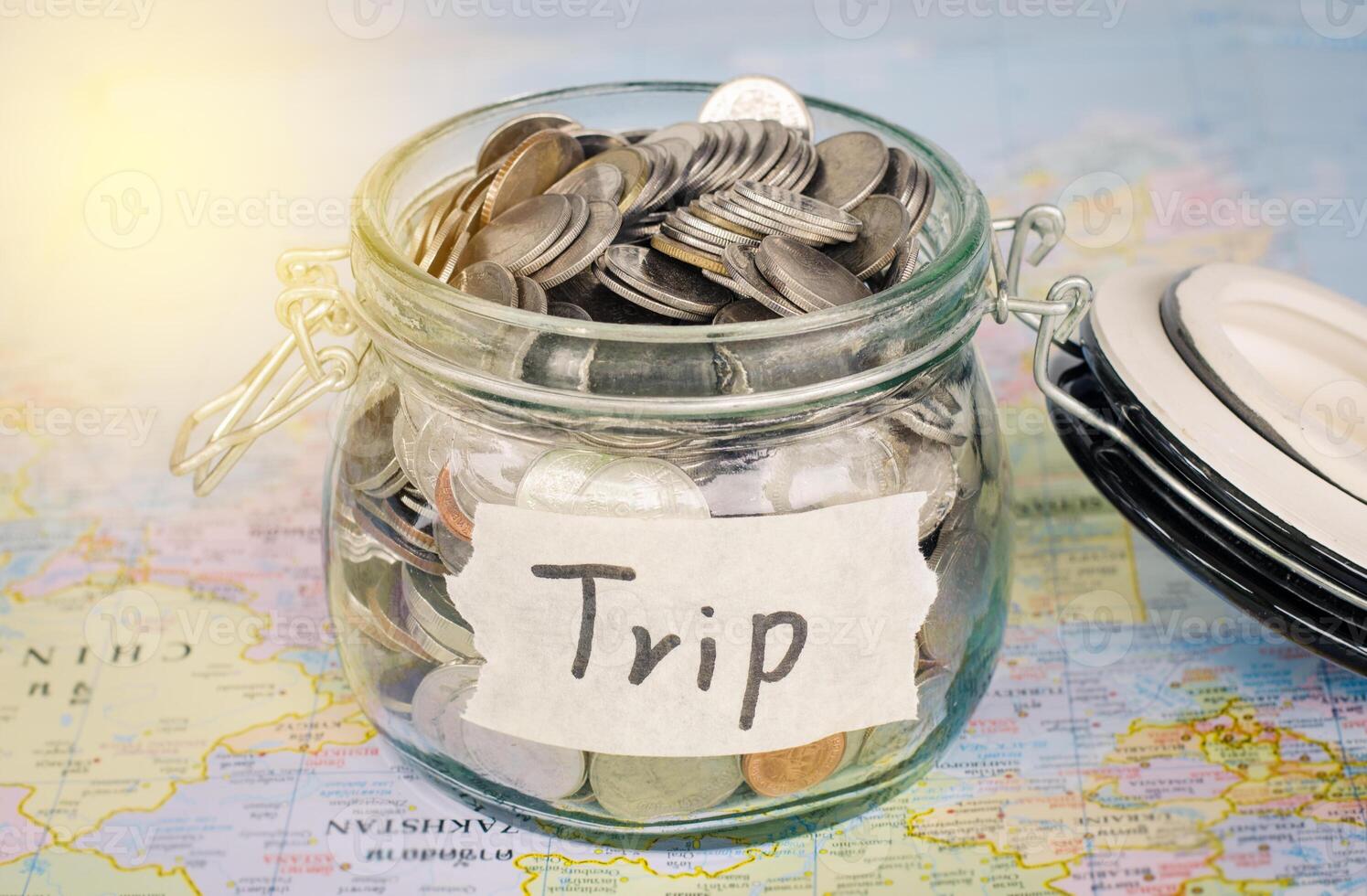 Target for travel - concept saving money in a glass and word trip on map photo