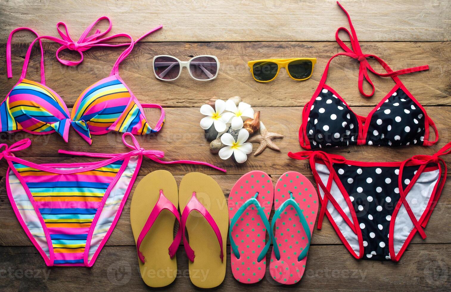 Bikinis, sunglasses, shoes, two sets placed on a wooden floor photo