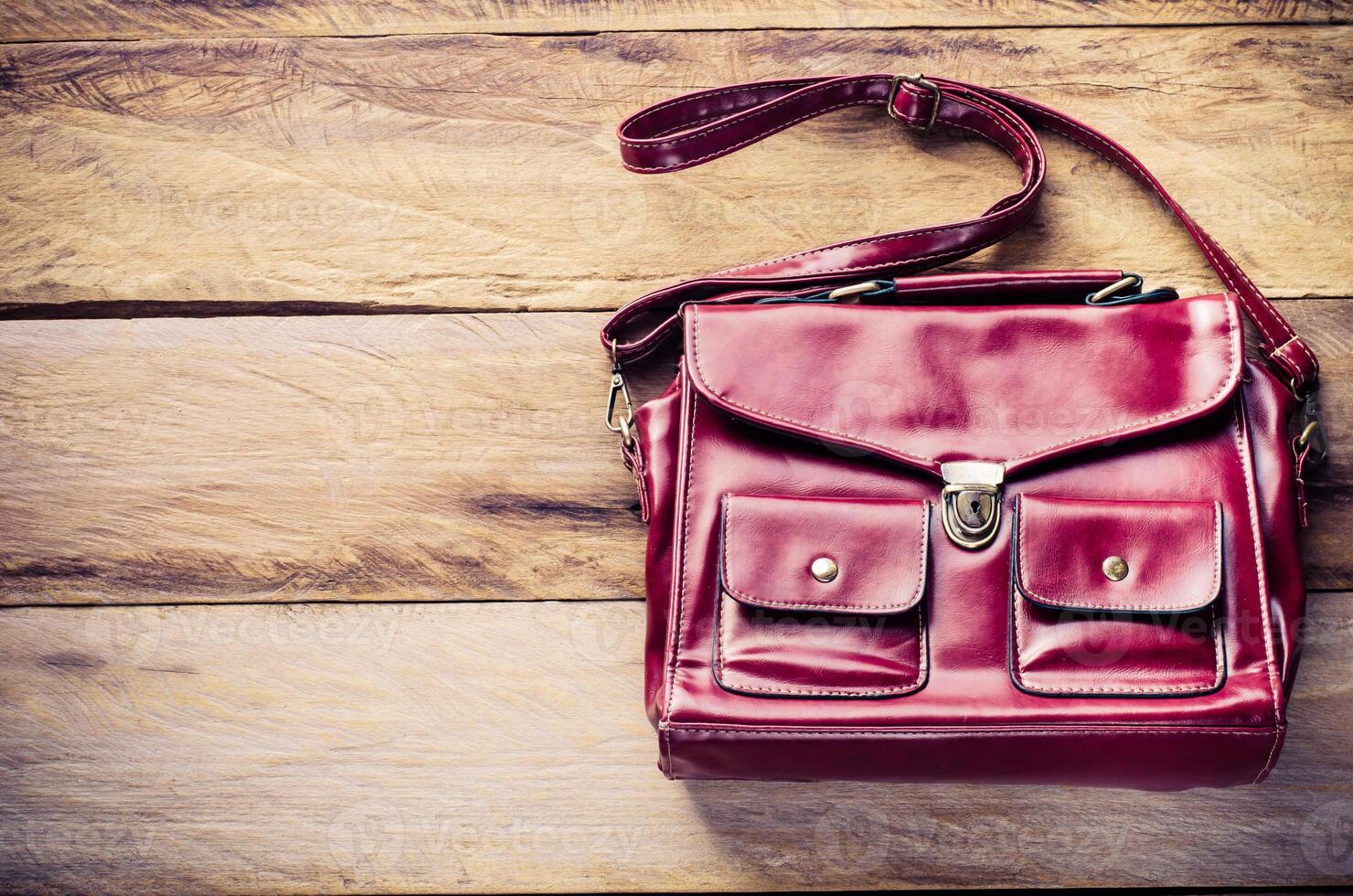 Red leather bag is placed on a wooden floor. photo