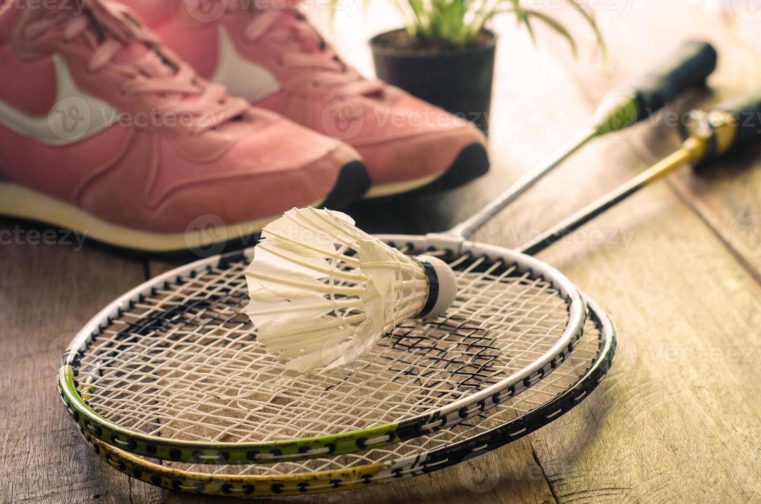 Shuttlecock and badminton racket with sport shoes on wooden floor for exercise photo