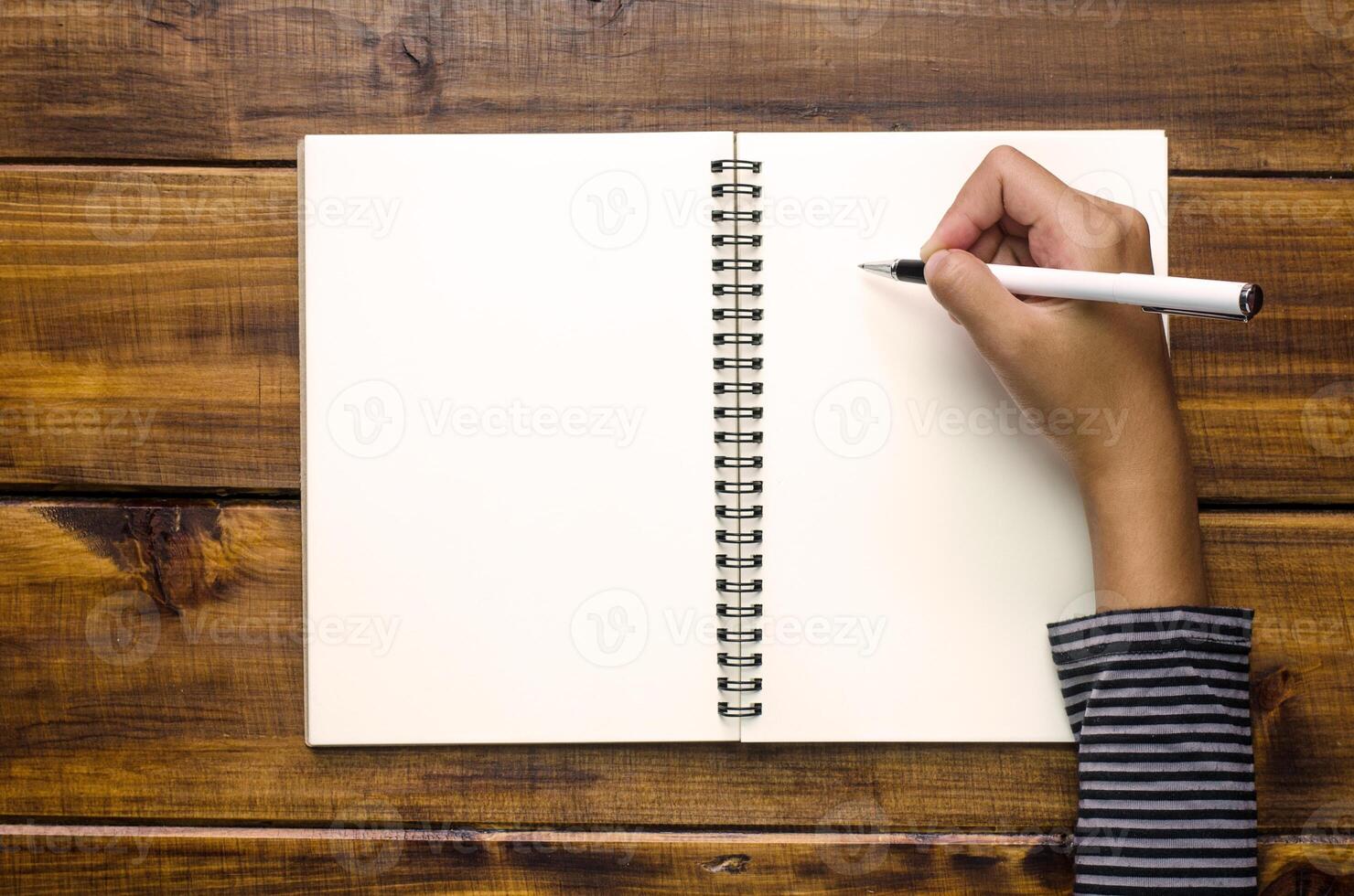 Hands are writing in a notebook on wooden floor photo