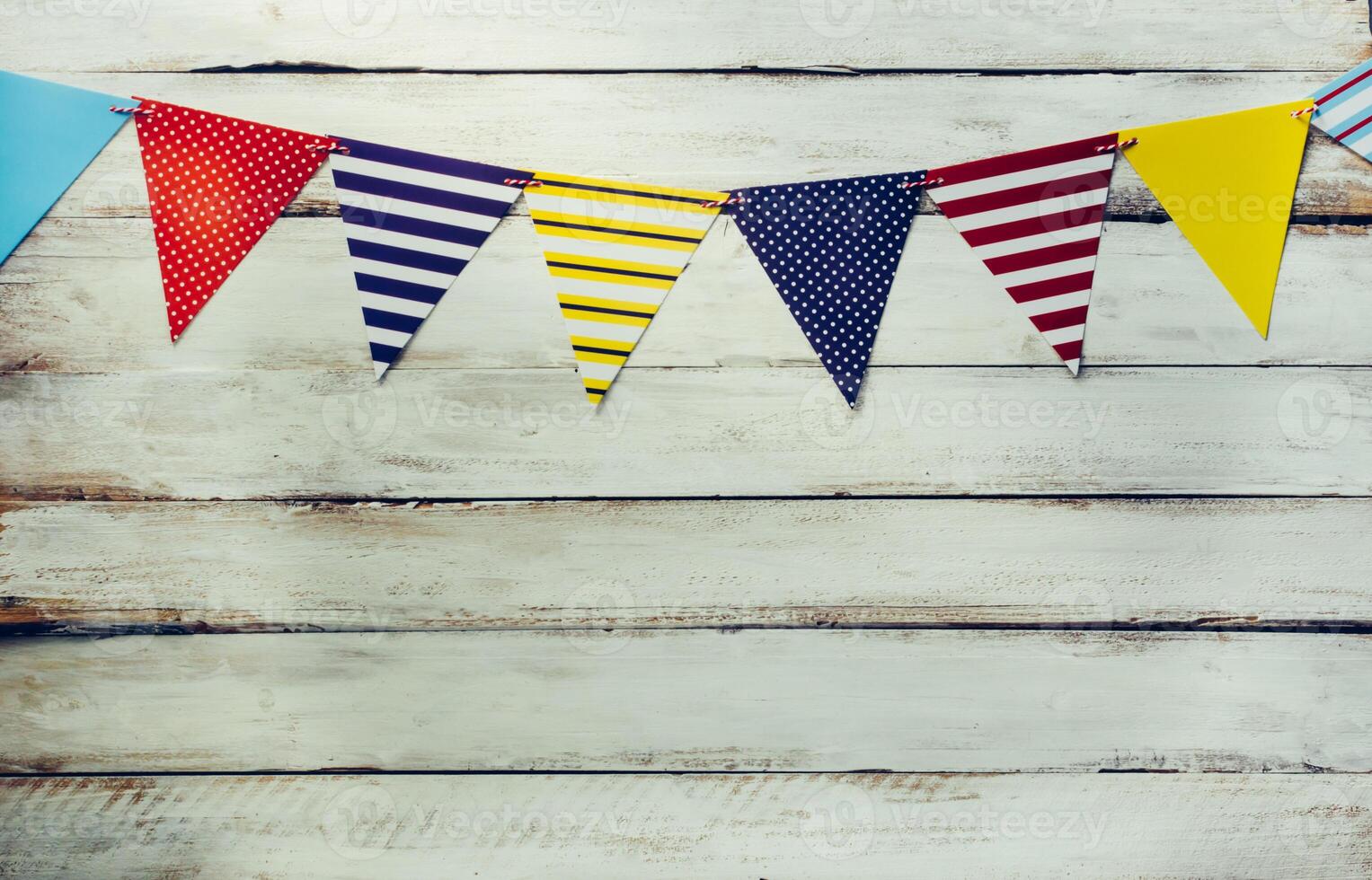 The colorful flag line decorating the banquet has white wooden floor as background. photo