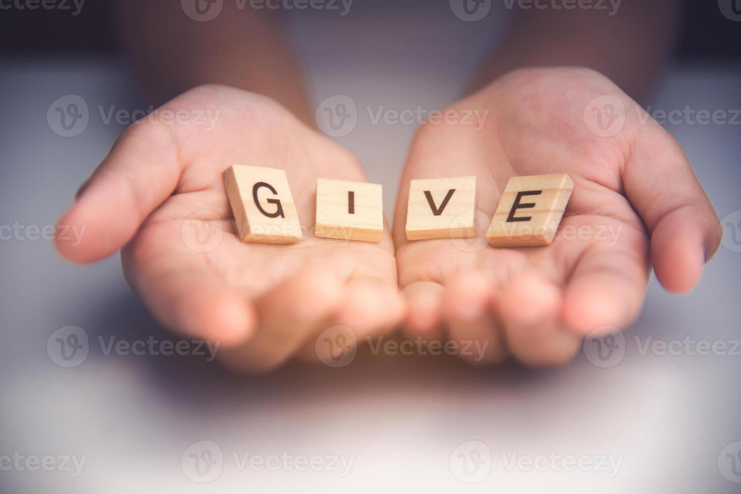 The word  GIVE  in hands in cupped shape. Concepts of sharing, giving, photo