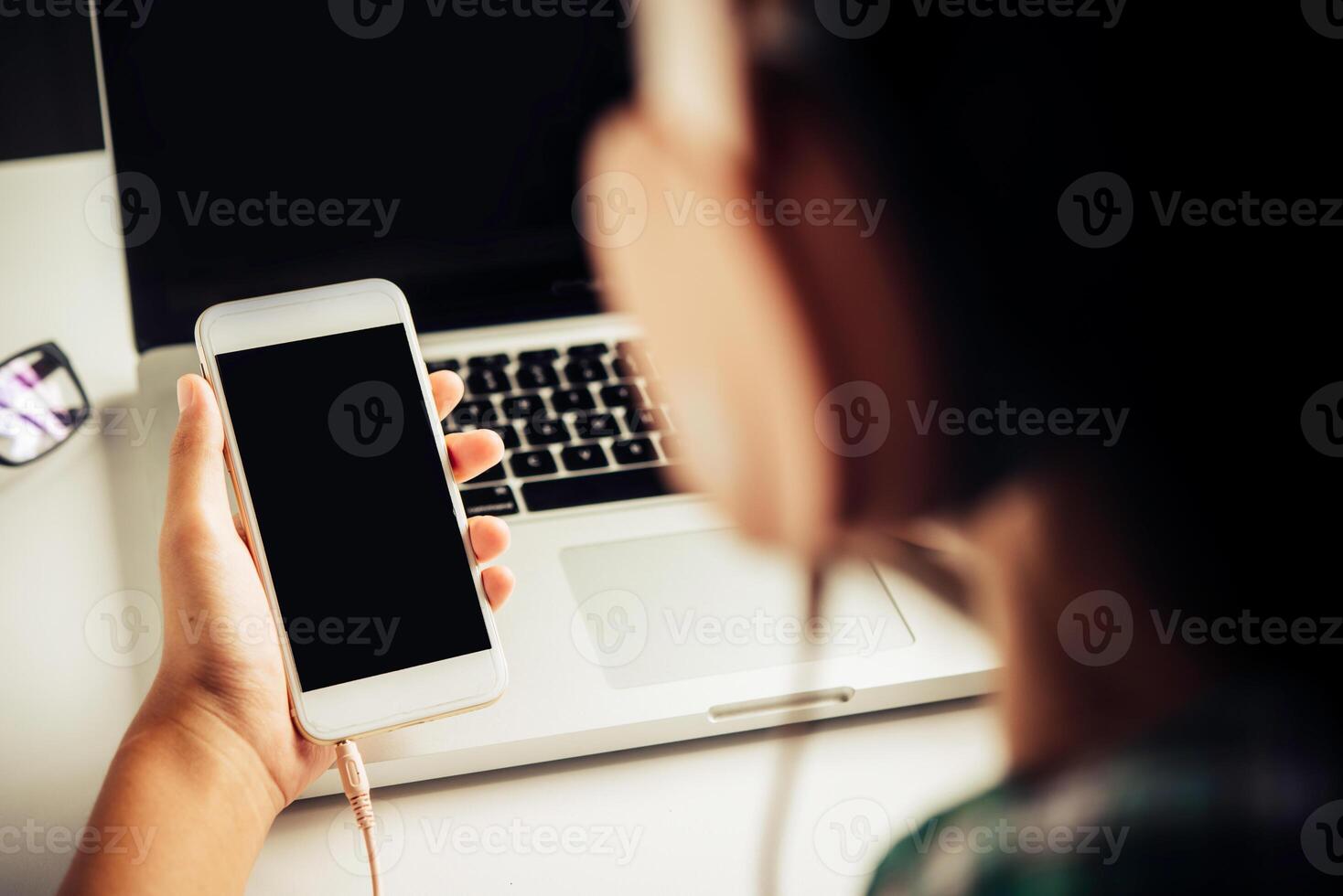 People are using a smartphone to listen to music and wear headphones. photo
