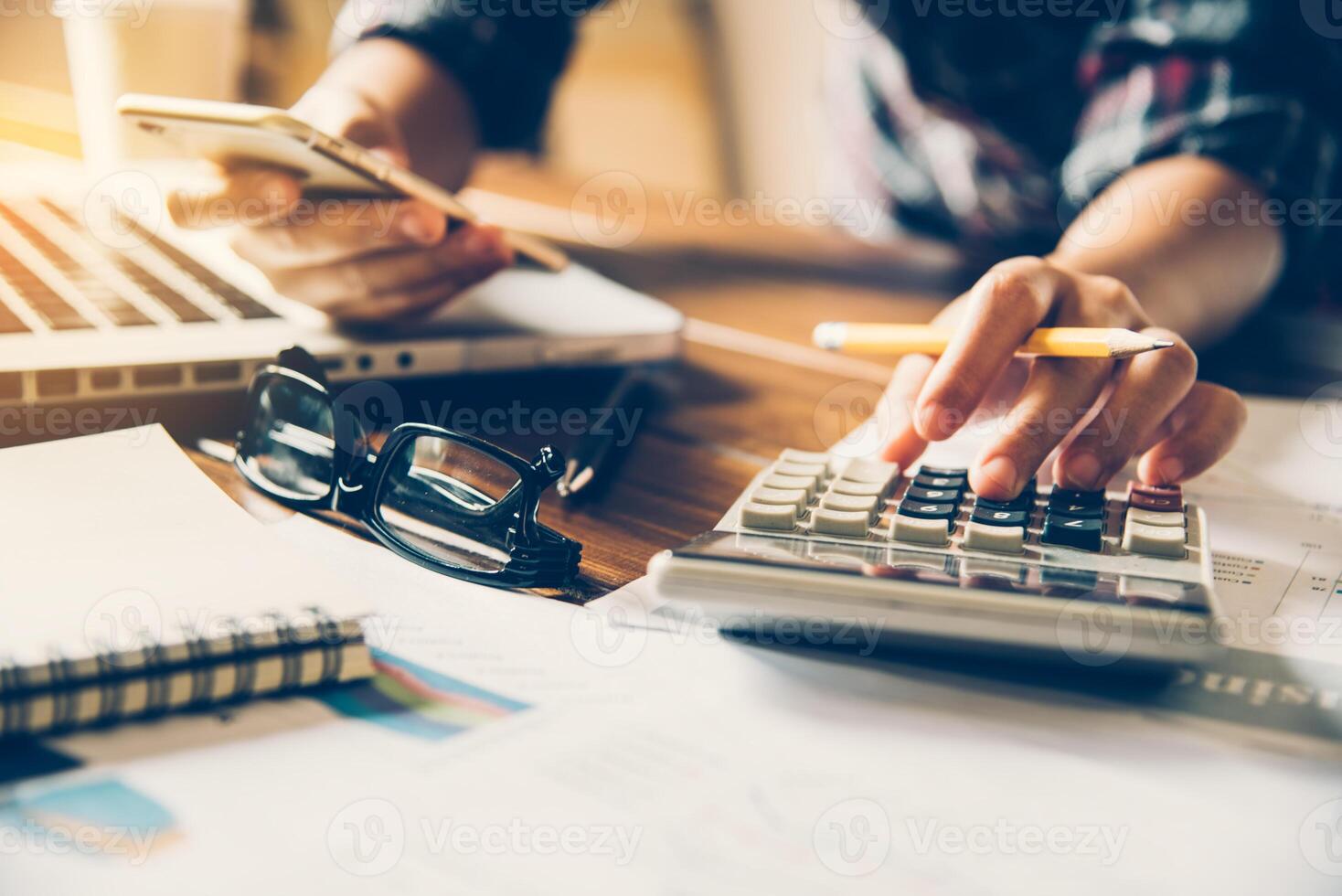 Business people are working on calculator and smartphone in business analysis with graphs and documentation laptop in office photo