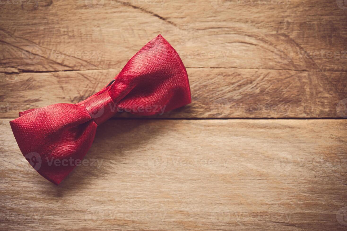 Red bow tie placed on wooden floor. photo