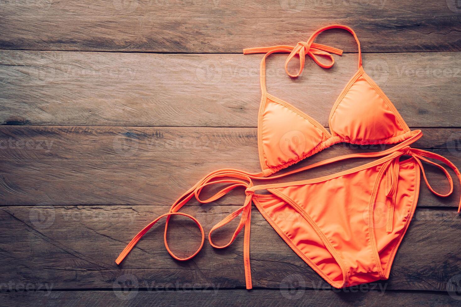 orange bikini rests on a wooden floor -summer and travel cocept. photo