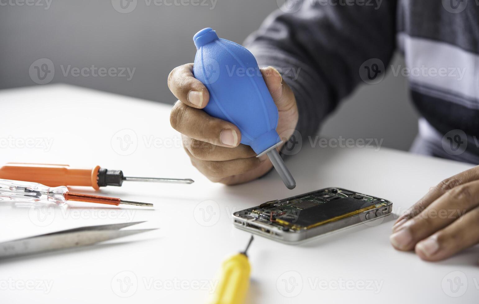 Repairman disassembling Repairman disassembling smartphone with screwdriver. photo