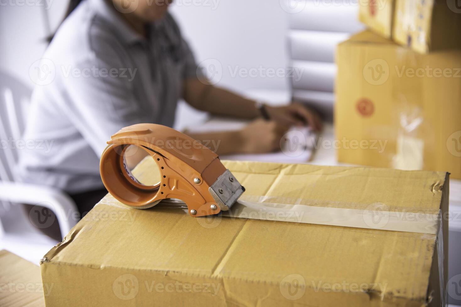 The staff is using the tape to pack the package goods to the customer. photo