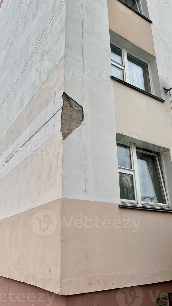 Damaged facade of a residential building. Chipped plaster on the facade. photo