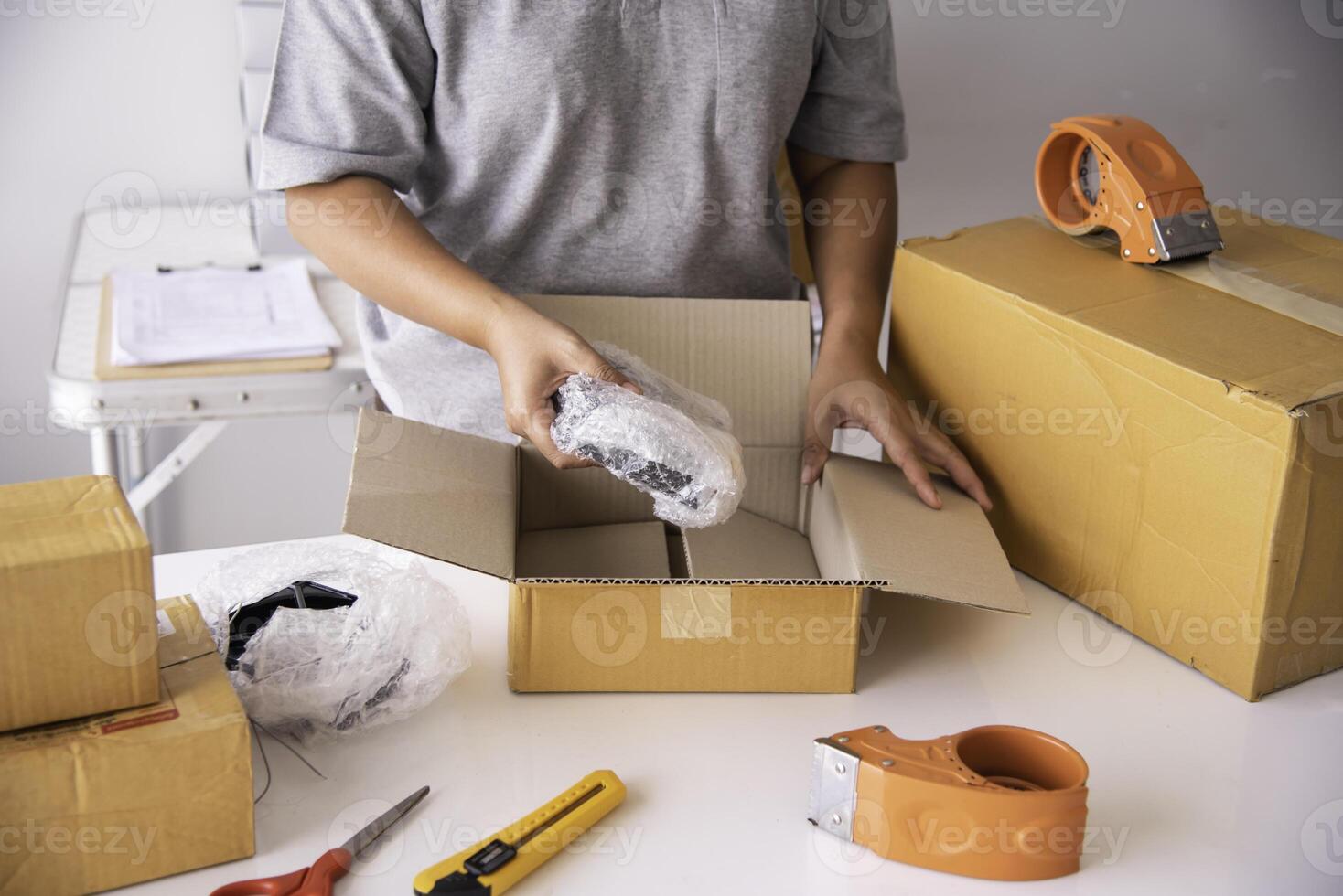 The staff is using the tape to pack the package goods to the customer. photo