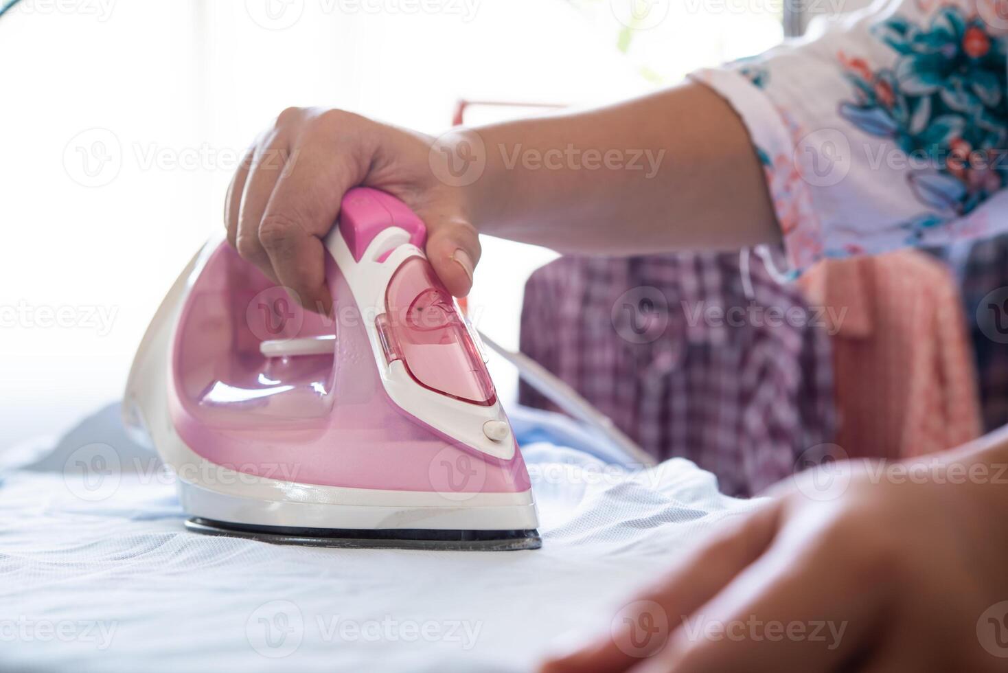 cerca arriba de mujer planchado ropa en planchado tablero foto