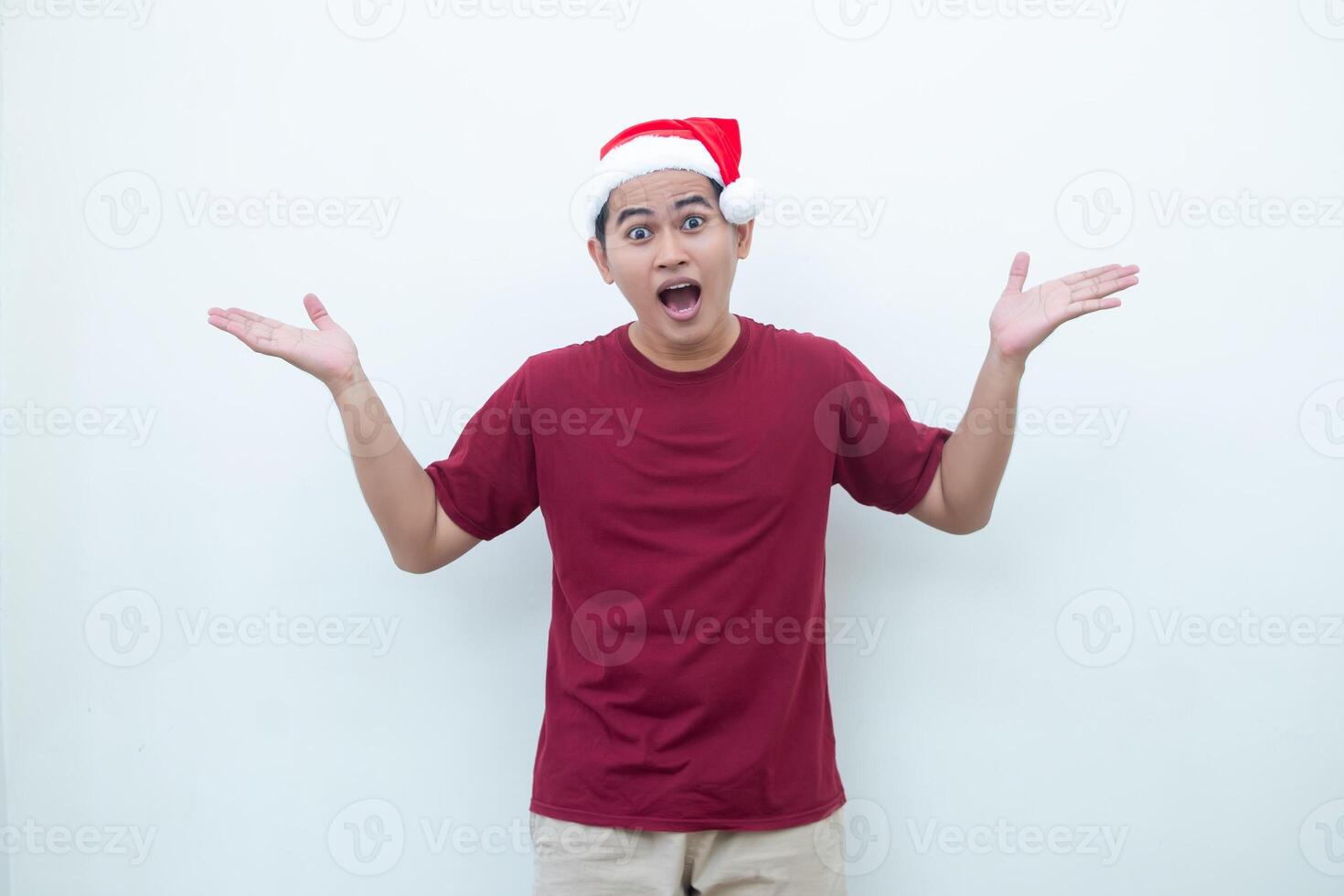 Young Asian man wearing a Santa Claus hat smiling, shock and pointing to her side isolated by white background for visual communication photo