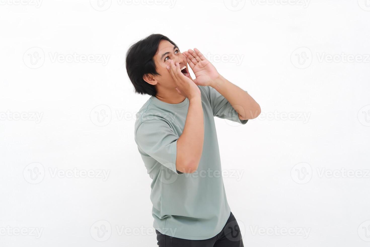 A young Asian man employee wearing tshirt is shouting and screaming loud with a hand on her mouth, isolated by white background. photo